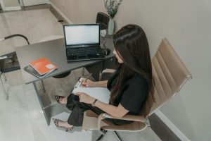 Woman working at a desk with a laptop and notebook.